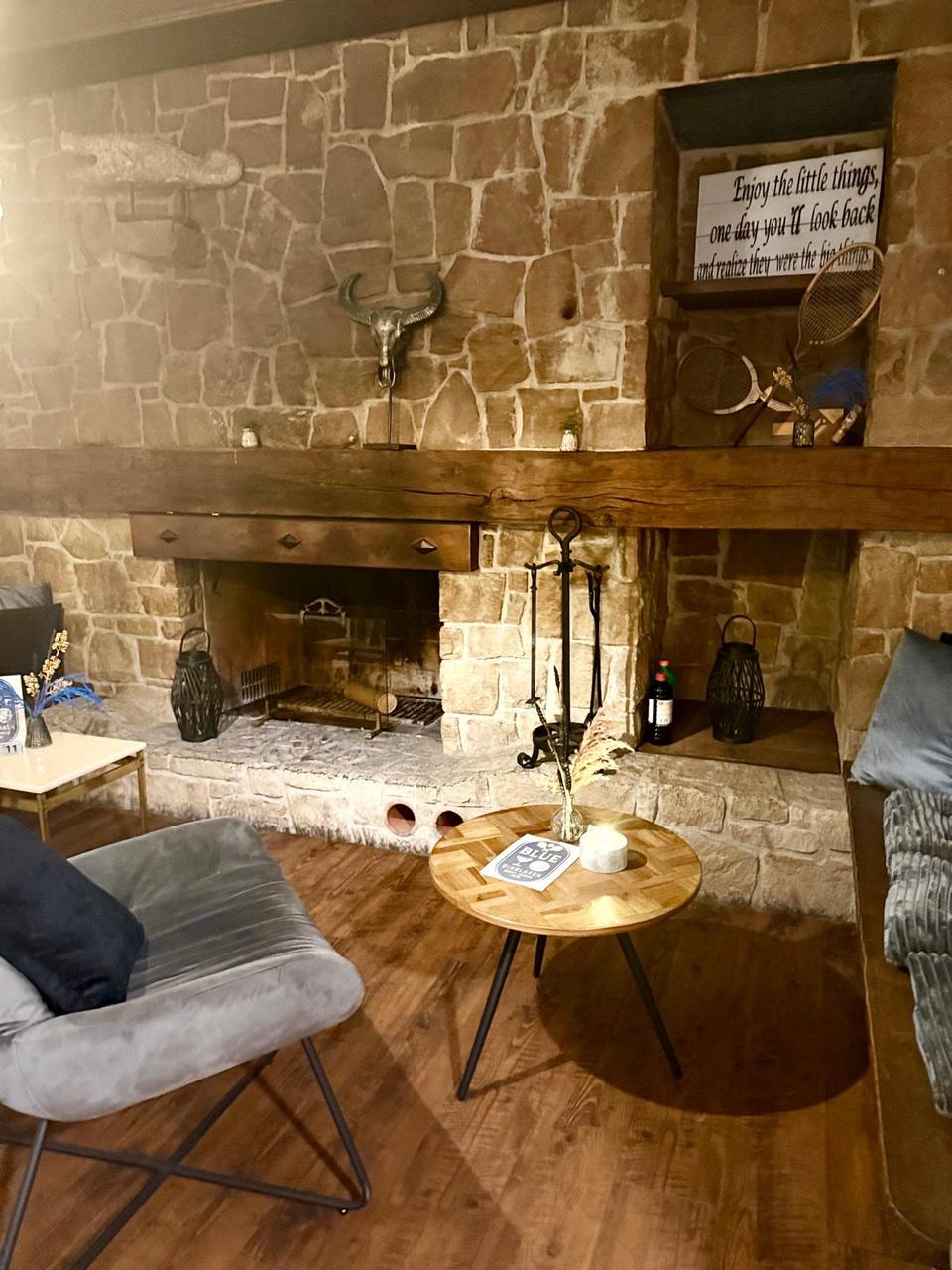 Kaminecke mit grauen Sesseln, Steinwand und kleinem Tisch