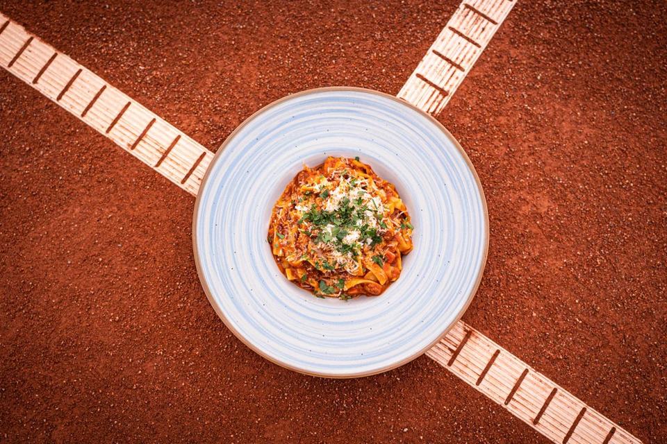 Tagliatelle in Tomatensoße, angerichtet auf dem Sandplatz