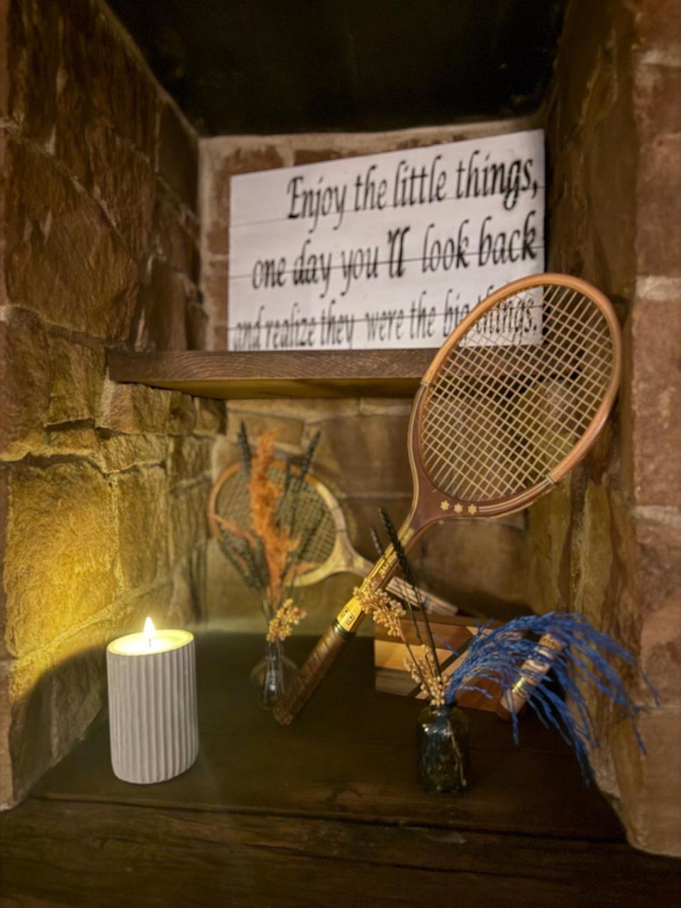 Deko-Ecke mit altem Holzschläger und Schild „Enjoy the little things“