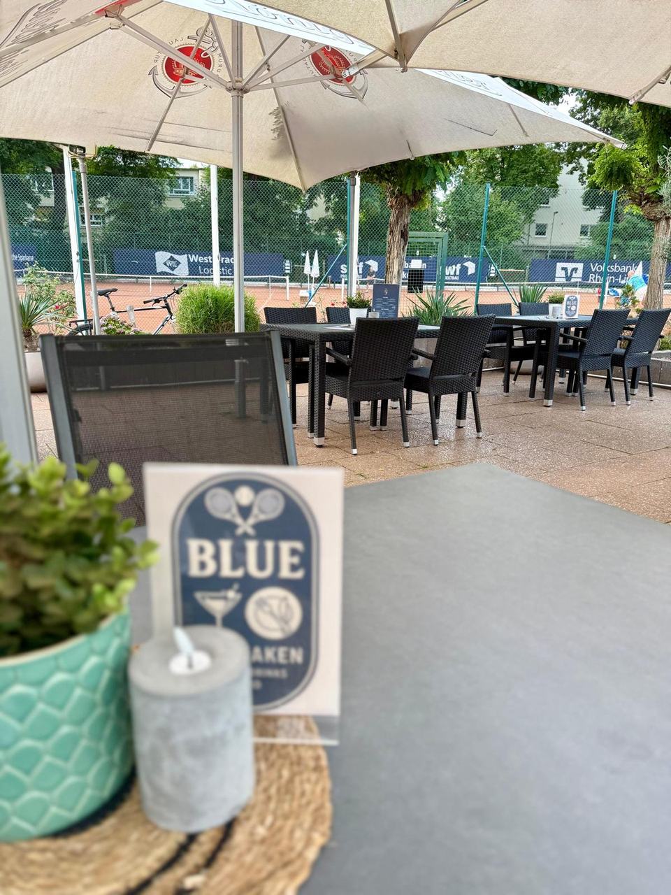 Terrasse mit Sonnenschirmen und Blick auf die Tennisplätze