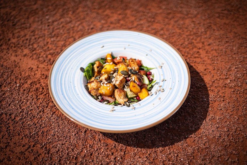 Salat mit gegrilltem Gemüse und Kernen auf dem Sandplatz